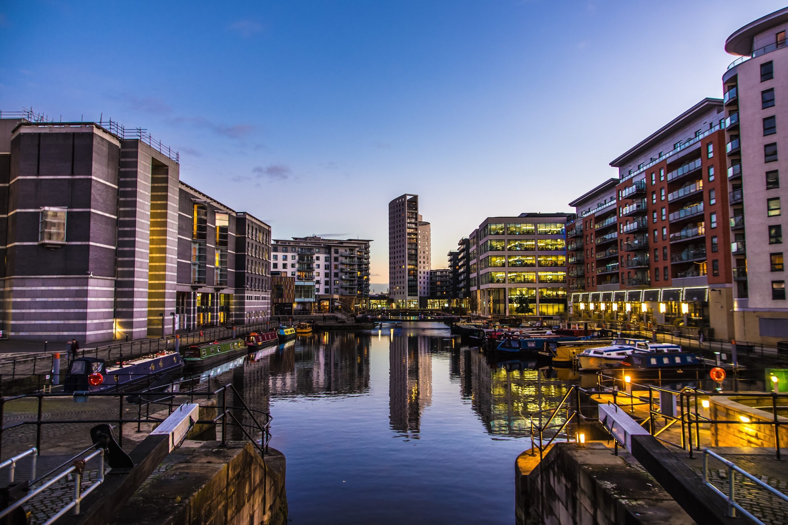 A dusk view of Leeds Dock showing the water, canal boats and apartments.